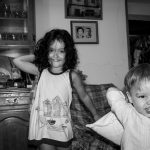 Una niña y un niño más pequeño, con los brazos como si fueran a lanzar algo mientras miran y sonríen a la cámara.