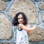Una niña posando a cámara con una pared de fondo.