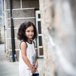 Una niña posando de perfil a la cámara en la calle.