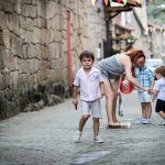 Una señora y tres niños en la calle de pueblo.