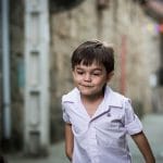 Un niño en la calle captado en cámara mientras juega con otros niños.