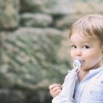 Un niño pequeño con un chupete mirando de reojo a la cámara.