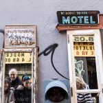 Una pared con puertas de ventana convertidas en espejo y un cartel que pone "Welcome to our home - Motel". De un puesto en plena calle.